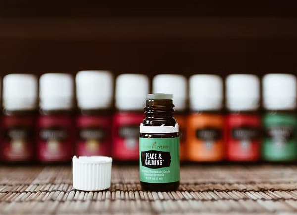 A focused bottle of "Peace & Calming" essential oil stands out against a backdrop of colorful bottles.