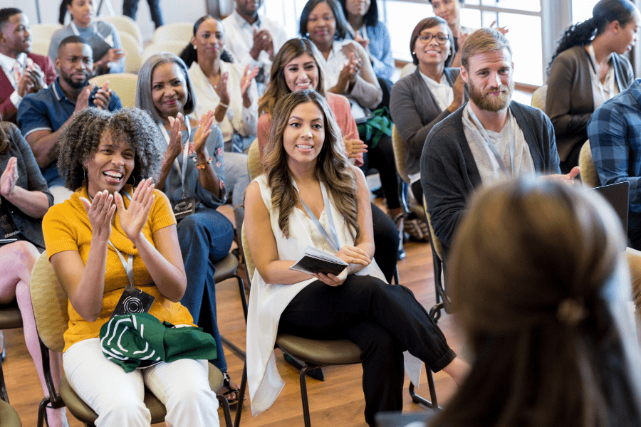 A diverse audience enthusiastically applauds during an event.